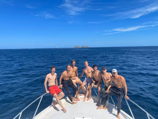 A group of learning scuba divers on the boat, with the Catalinas island in the background